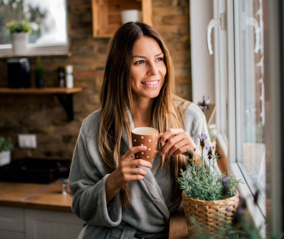 Young woman drinking coffee in the morning, looking at window