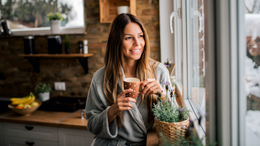 Young woman drinking coffee in the morning, looking at window