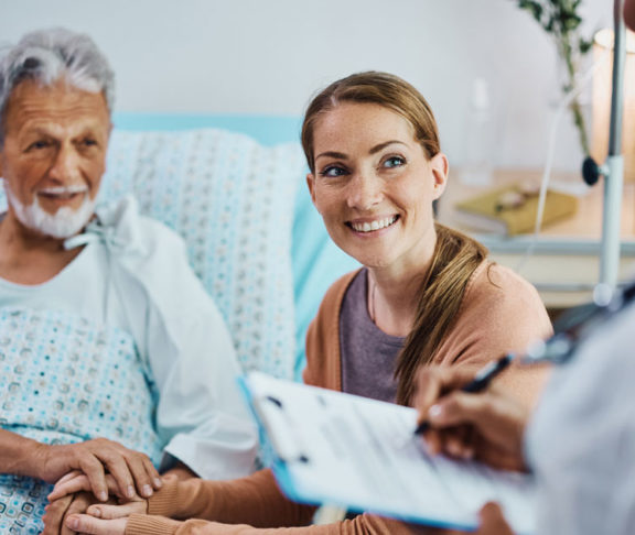 Happy woman and her hospitalized father talking to a doctor at the clinic