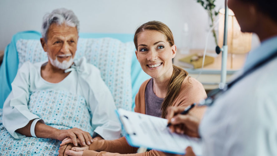 Happy woman and her hospitalized father talking to a doctor at the clinic