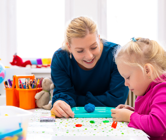 Toddler girl in child occupational therapy session doing sensory playful exercises with her therapist