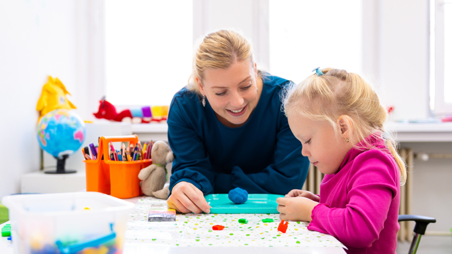 Toddler girl in child occupational therapy session doing sensory playful exercises with her therapist