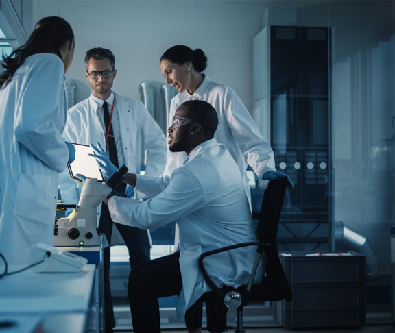 Medical Science Laboratory with Diverse Multi-Ethnic Team of Microbiology Scientists Have Meeting on Developing Drugs, Medicine, Doing Biotechnology Research. Working on Computers, Analyzing Samples