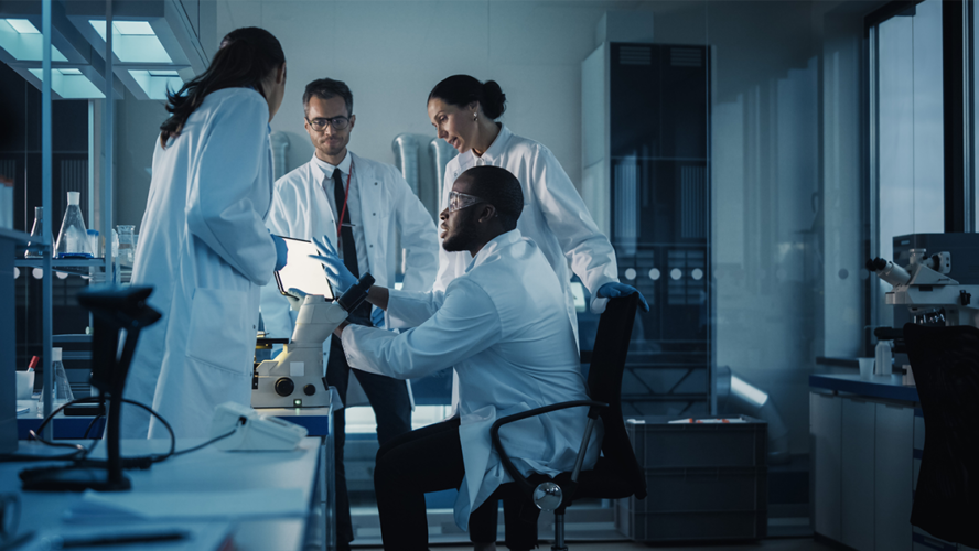 Medical Science Laboratory with Diverse Multi-Ethnic Team of Microbiology Scientists Have Meeting on Developing Drugs, Medicine, Doing Biotechnology Research. Working on Computers, Analyzing Samples