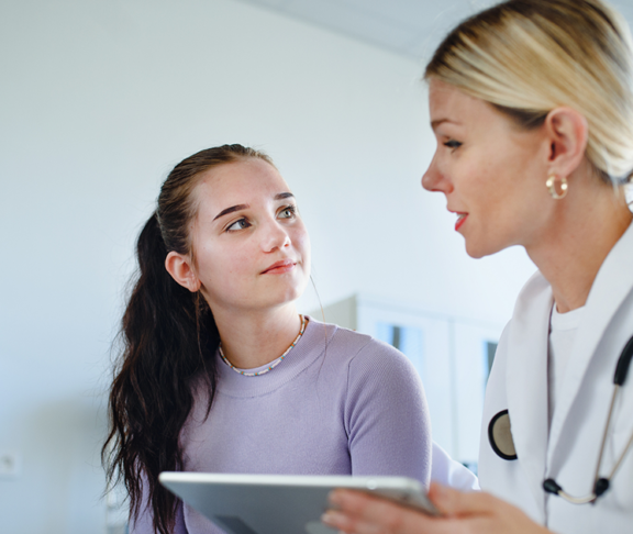 Young woman doctor explaining diagnosis to teenage girl